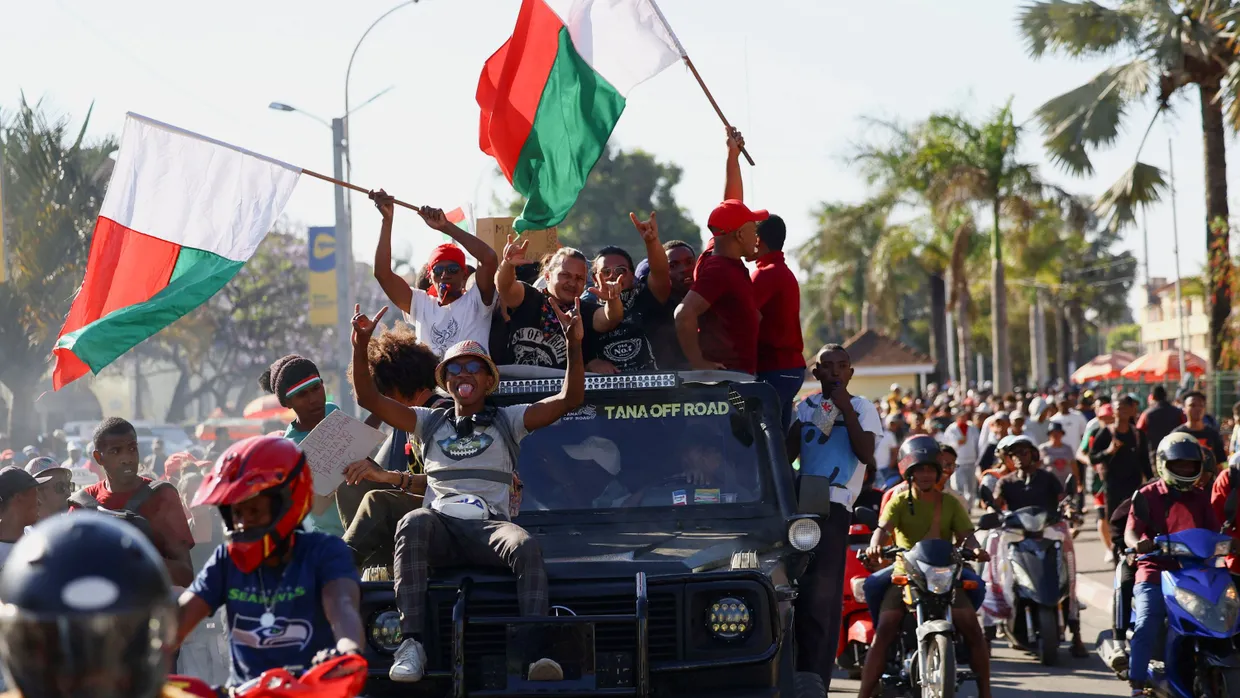 Ein Pickup-Truck fährt am Dienstag durch Antananarivo, Madagascar. Die Insassen schwenken Fahnen, nachdem sich das Militär den Demonstranten angeschlossen hat.