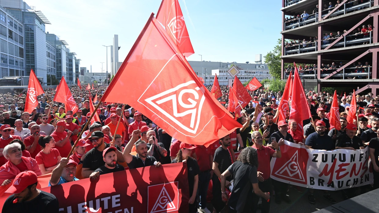 In einem Eingang zum Mercedes-Benz Werk demonstrieren am 03.07.2026 mehrere tausend Mitarbeiter des Automobilherstellers Mercedes-Benz mit Fahnen der Gewerkschaft IG Metall gegen den verschärften Sparkurs.