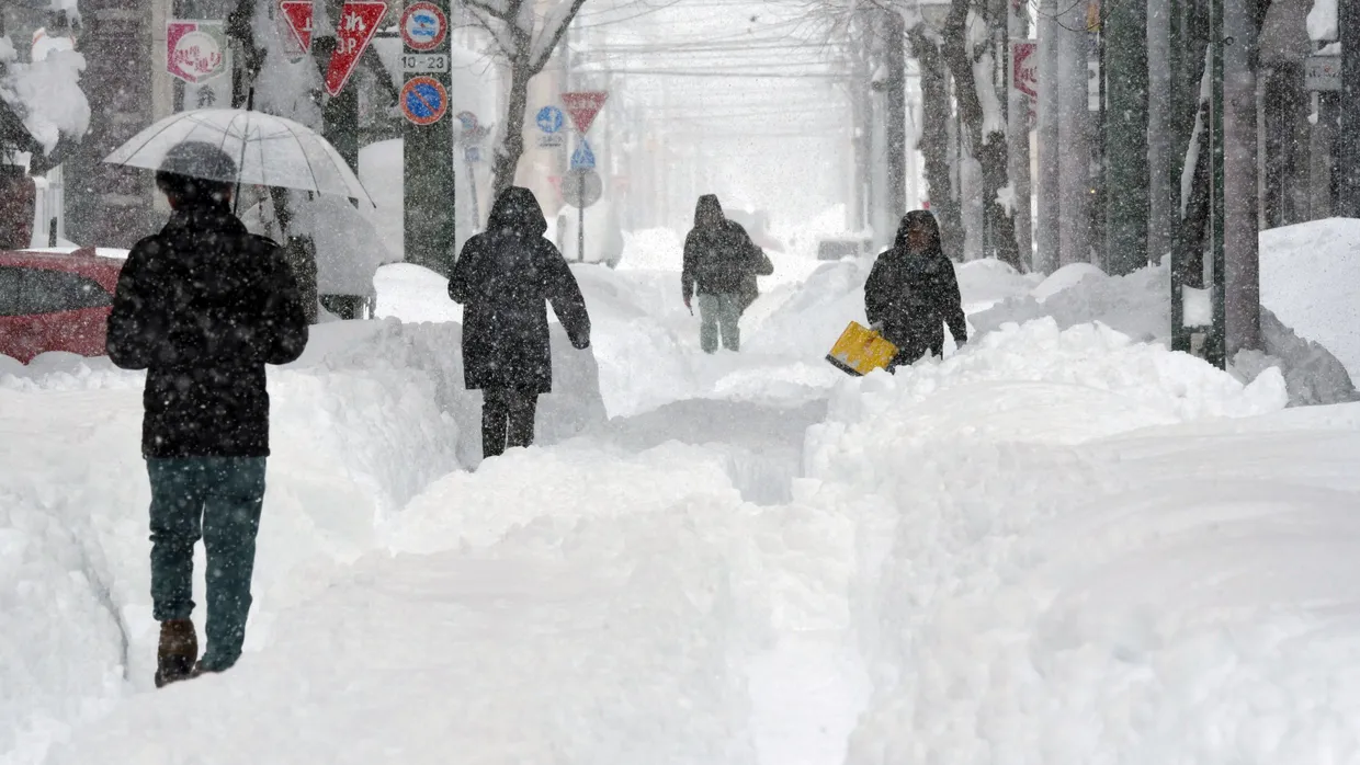 Menschen kämpfen sich durch schneebedeckte Straßen nach heftigem Schneefall in Obihiro.