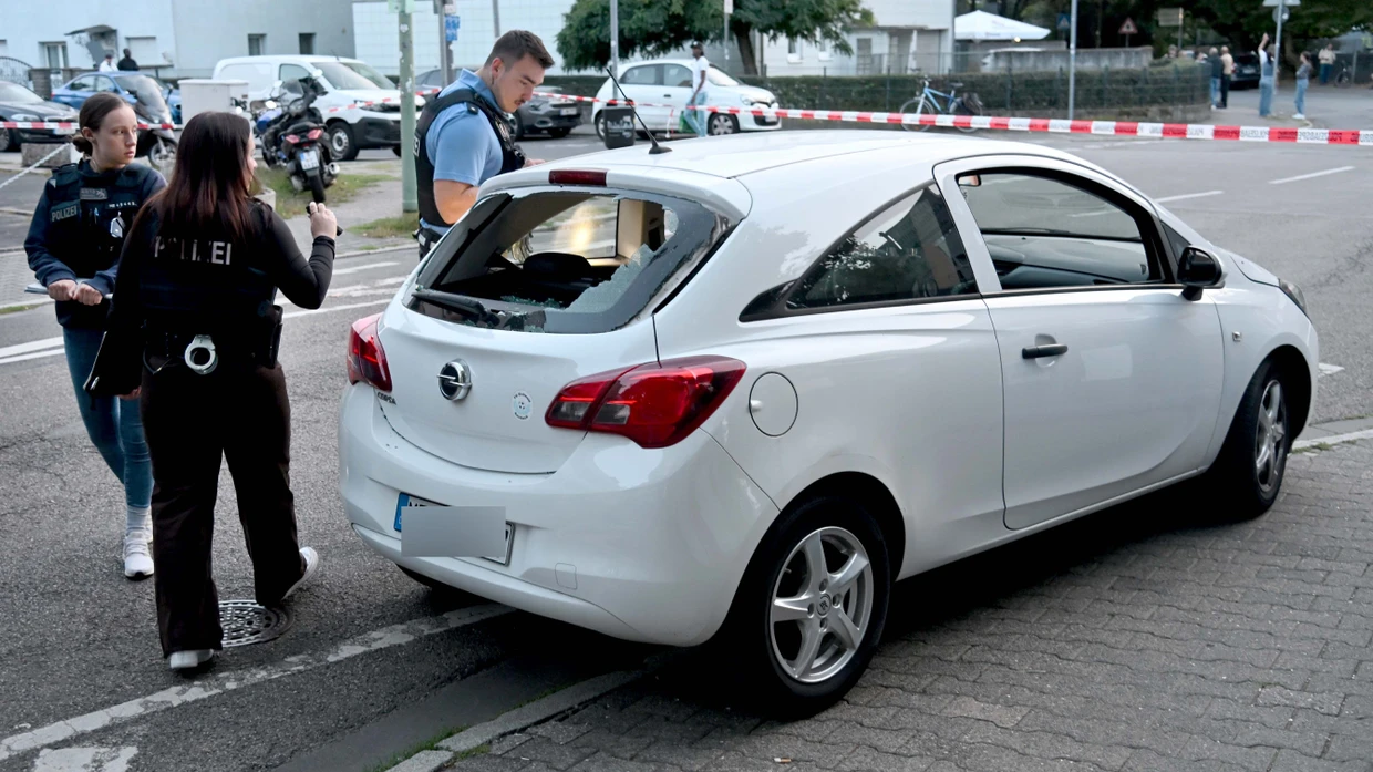 Zerstörte Heckscheibe: Polizisten inspizieren das von Schüssen getroffene Auto.