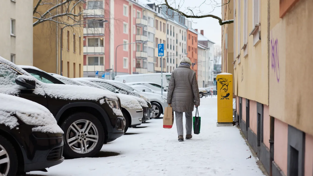 Gefährliches Pflaster: Eine ältere Frau mit Einkaufstaschen ist im Frankfurter Gallusviertel auf dem schneebedeckten Bürgersteig unterwegs.