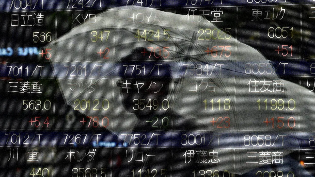 Steigende Kurse: ein Mann spiegelt sich in der Scheibe vor einer Anzeigetafel mit den Börsenkursen in Tokyo