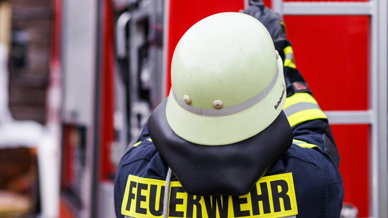 Ein Feuerwehrmann holt eine Leiter vom Dach eines Einsatzfahrzeugs (Symbolbild).