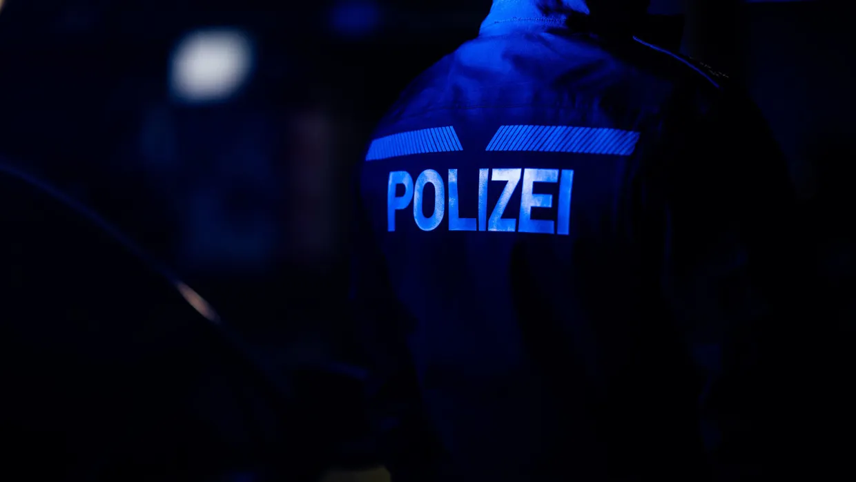 Ein Polizist steht im Januar neben einem Polizeiauto.