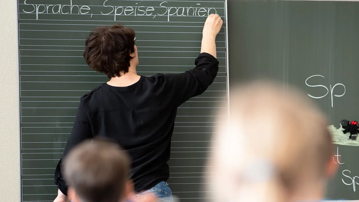 Eine Lehrerin schreibt in einer Schule an eine Tafel.
