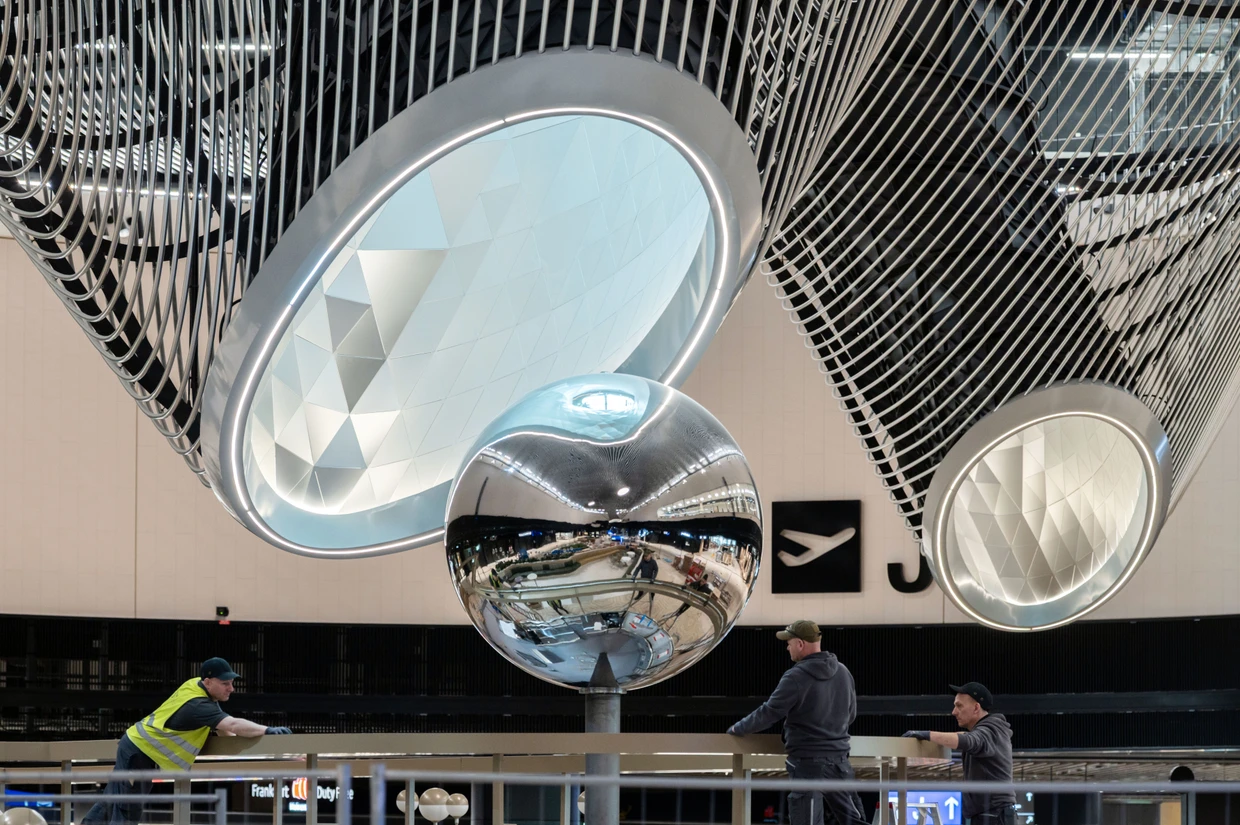 Arbeiter unter der "Lava-Decke" des Marktplatzes zwischen Sicherheitskontrolle und Gates im Terminal 3