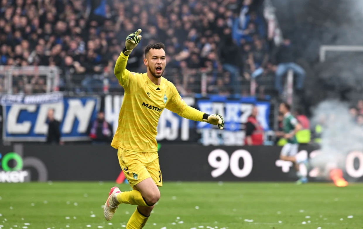 Die Bremer um Torwart Mio Backhaus jubeln, im Hintergrund zündeln die Hamburger Anhänger.