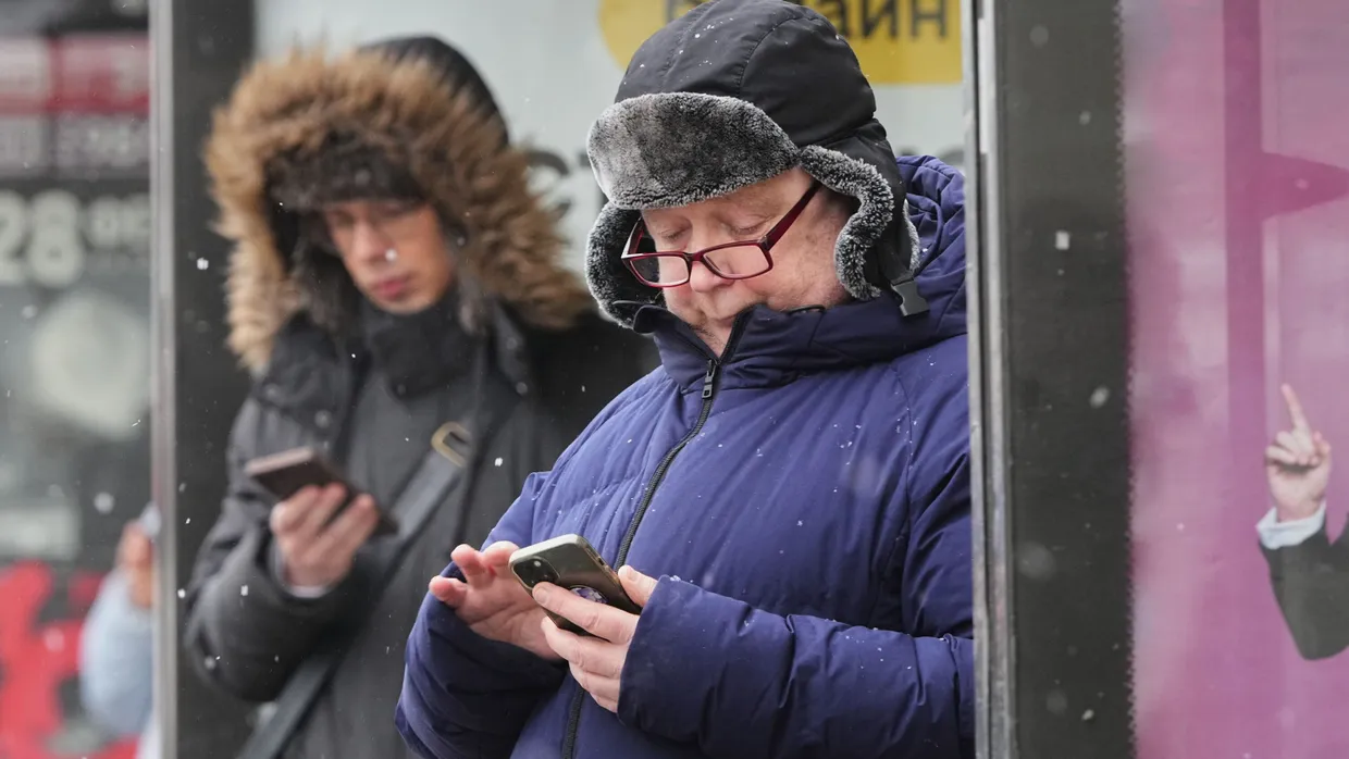Auf Telegram sollen sie nicht mehr schauen: Menschen schauen auf ihre Smartphones an einer Bushaltestelle in St. Petersburg.
