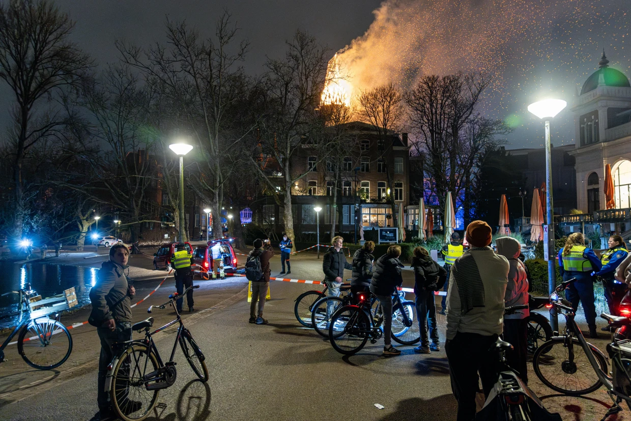 Passanten betrachten hinter eine Absperrung die brennende Kirche.