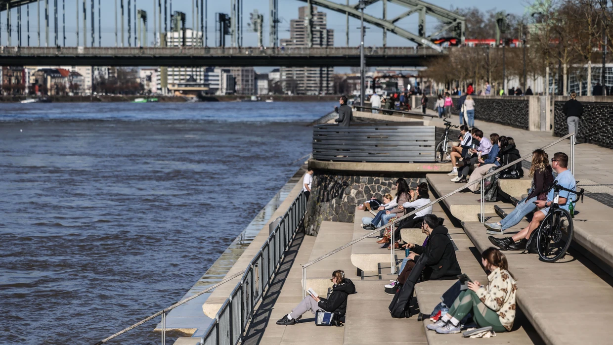Menschen sitzen in der Sonne am Kölner Rheinufer. Nach einigen Wochen mit hartnäckigem Winterwetter kehrt das Frühlingswetter mit Spitzenwerte von fast 20 Grad ein.