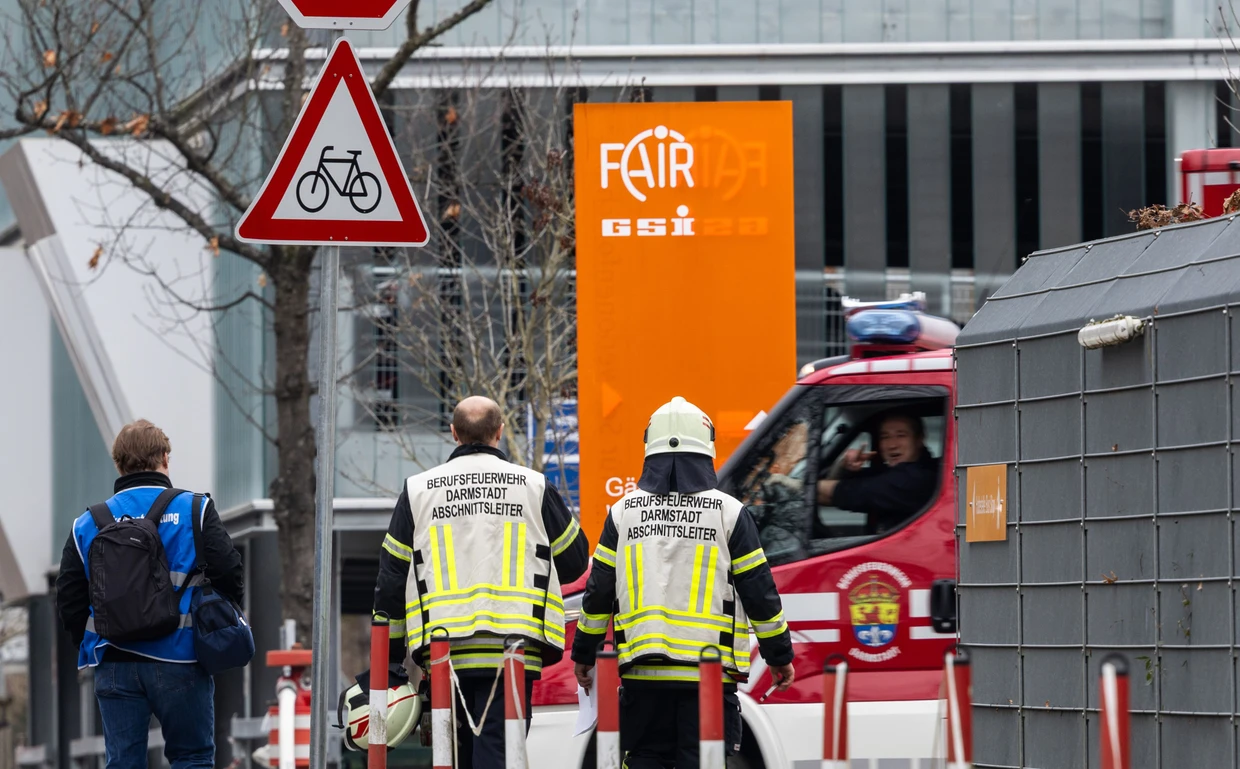 Feuerwehrmänner laufen auf das Gelände des GSI Helmholtzzentrums für Schwerionenforschung in Darmstadt.