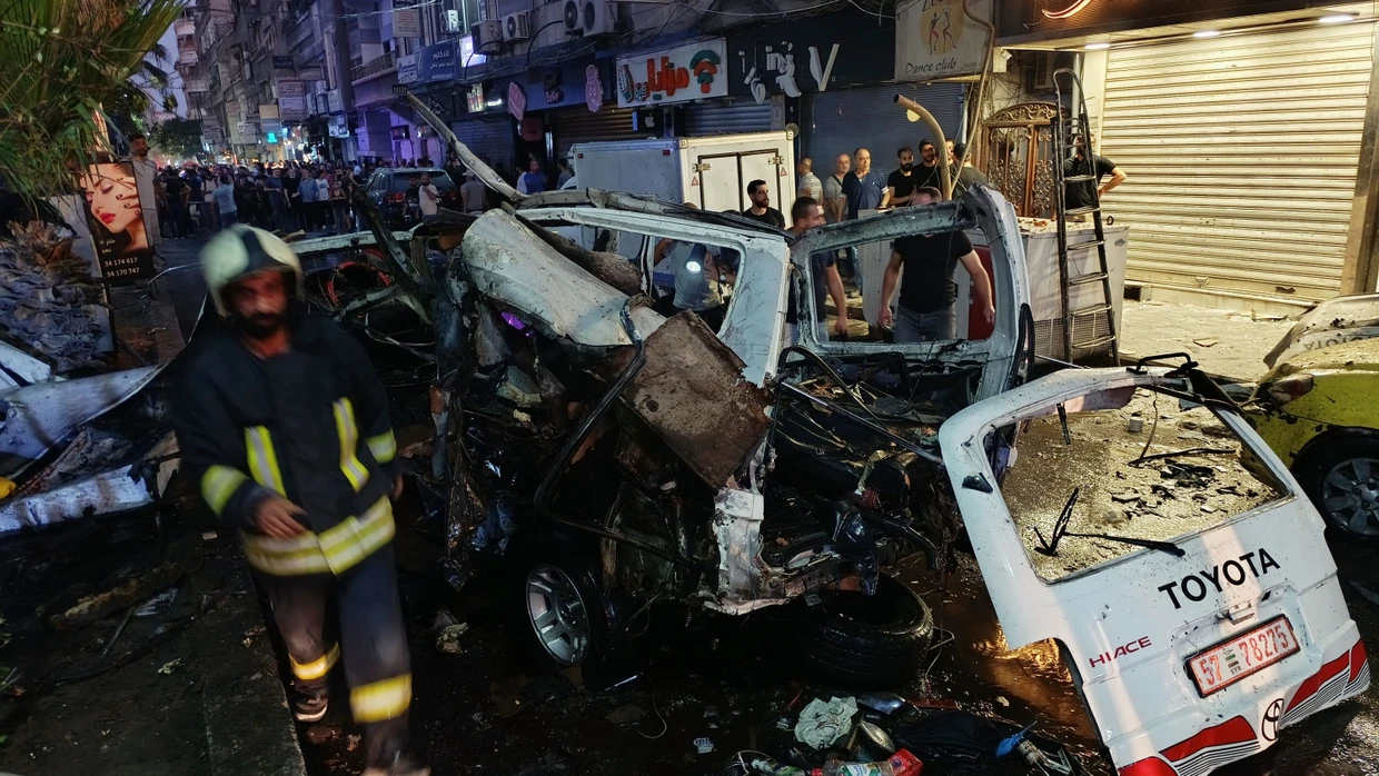 Syrische Feuerwehrleute und Rettungskräfte begutachten am Ort einer Explosion im Vorort Dscharamana beschädigte Fahrzeuge.