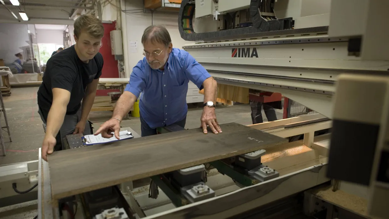 Ans Brett: Lehrling Marco Giedeler mit Schreinermeister Gerhard Luther an der CNC-Fräse – damit lassen sich sogar Fotomotive ins Holz schnitzen.
