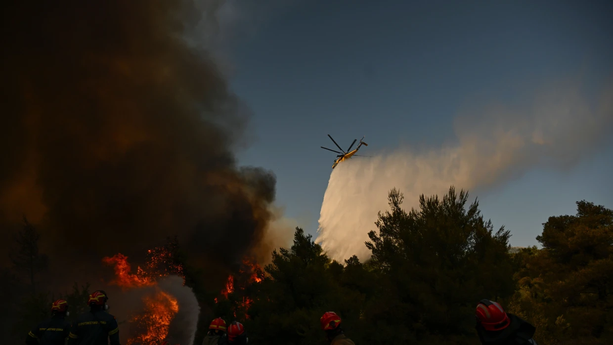 Ein Löschhubschrauber wirft am Sonntag bei einem Waldbrand in der Nähe von Porto Germeno nordwestlich von Athen Löschmittel über einen rauchverhangenen Wald ab.