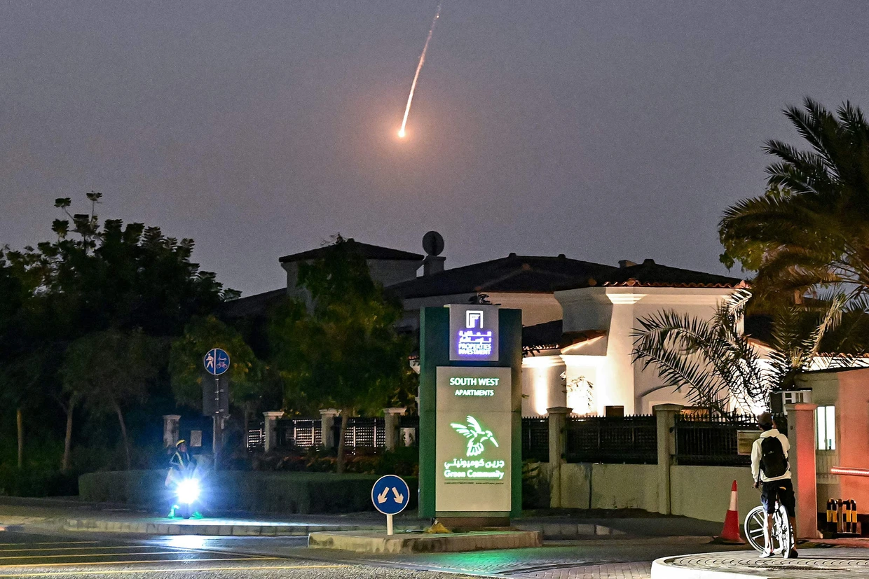 A cyclist watches a missile fly over the Dubai sky on February 28.