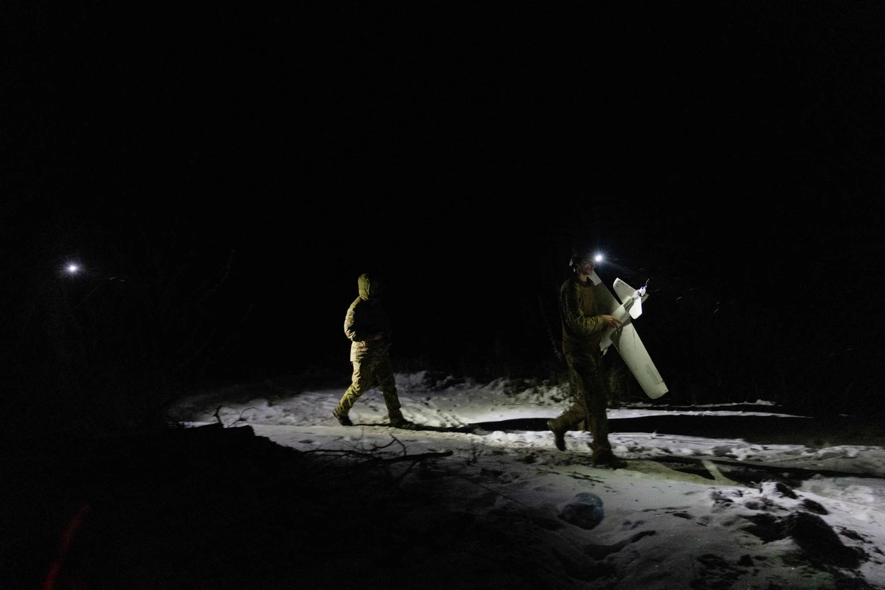 Ukrainische Soldaten tragen eine Abfangdrohne durch den Schnee.