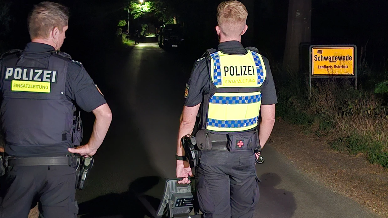 Zwei Polizisten stehen mit einem mobilen Scheinwerfer am Ortseingang von Schwanewede.