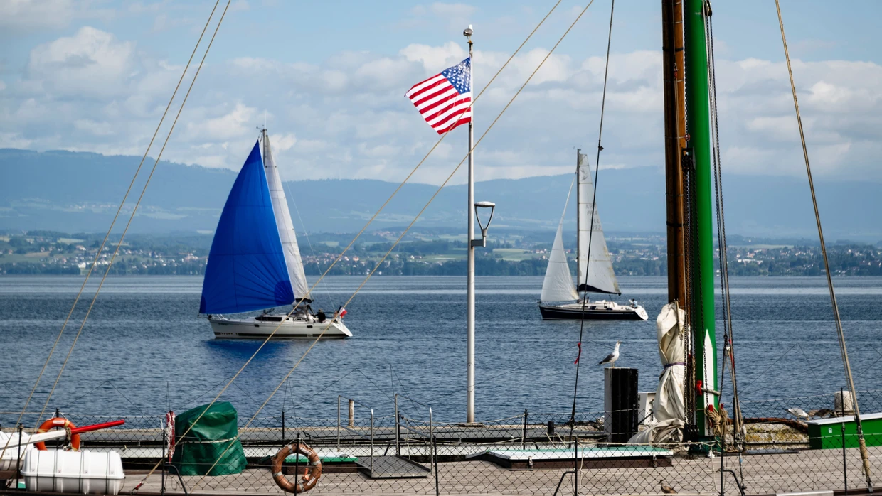 Die Welt zu Gast in Évian: US-Flagge vor Booten auf dem Genfer See