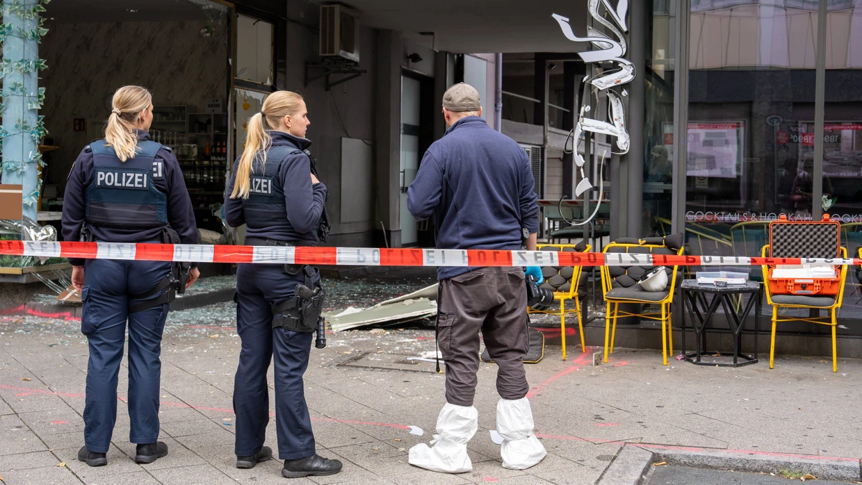 Polizisten stehen vor der zerstörten Bar in Offenbach: Scheiben sind zerborsten, der Schriftzug über der Tür heruntergefallen.
