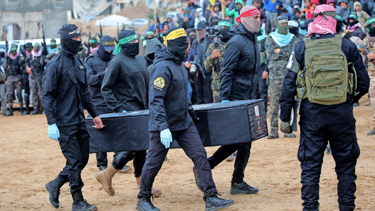 Kämpfer der Hamas übergeben am 20. Februar einen Sarg mit den sterblichen Überresten einer israelischen Geisel an Mitarbeiter des Internationalen Kommitees des Roten Kreuzes.