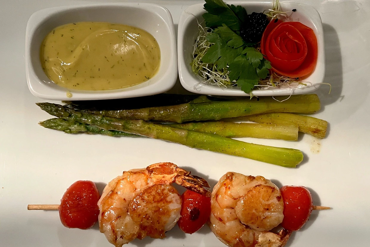 Riesengarnelen-Jakobsmuschelspieß an frischem, grünem Spargel