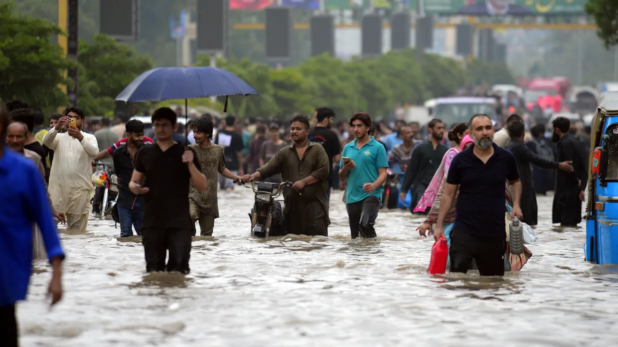 Menschen waten nach starkem Monsunregen durch eine überflutete Straße in Karachi, Pakistan.
