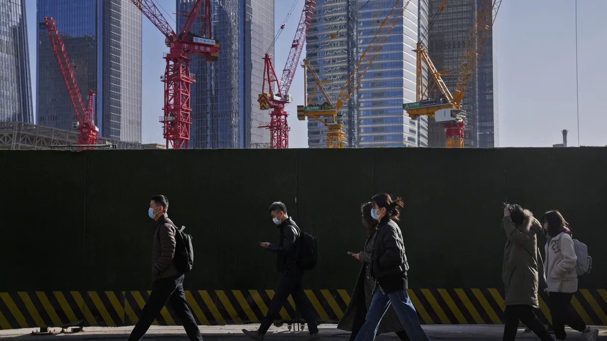 Menschen gehen an Baukränen im zentralen Geschäftsviertel in Peking vorbei. Chinas Wirtschaft ist im November weiter in die Deflation gerutscht.