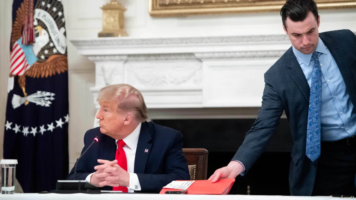 Nicolas Luna, Assistent des Präsidenten, reicht Donald Trump während eines Gesprächs einen Ordner