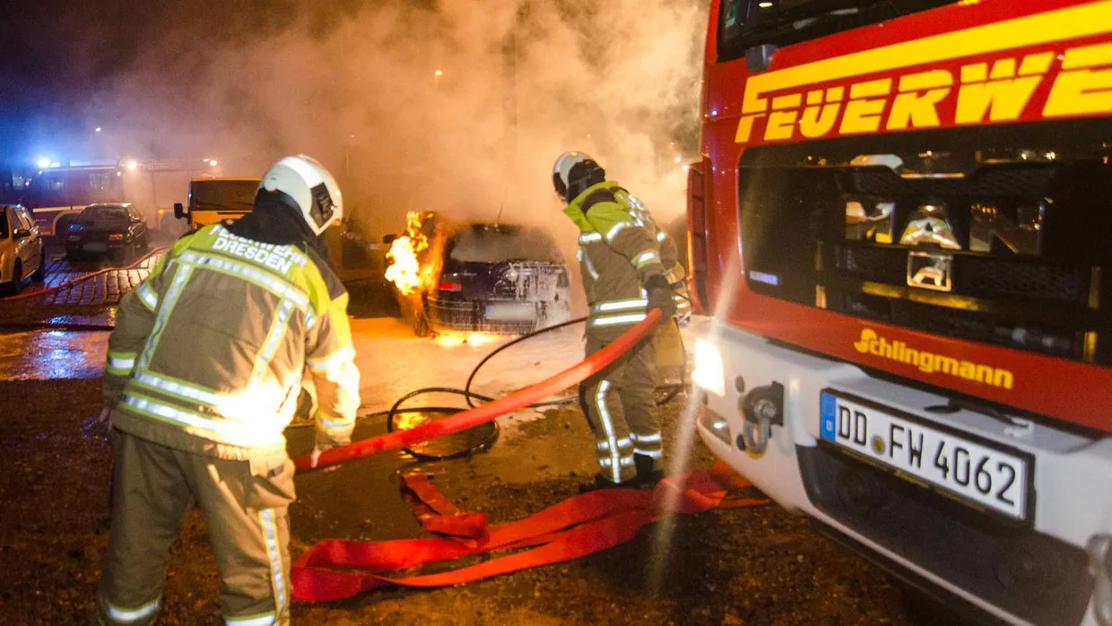 Feuerwehrleute versuchen ein brennendes Auto zu löschen.