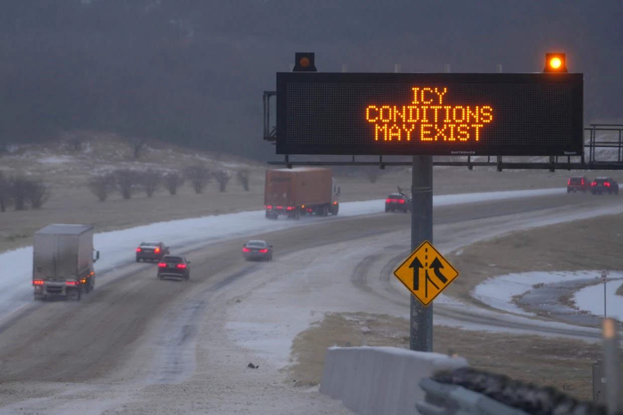 „Es könnte glatt sein“: Fahrzeuge fahren auf der Interstate-20 in Richtung Osten an einem Schild vorbei, das Autofahrer während eines Wintersturms in Dallas auf mögliche Glätte hinweist.