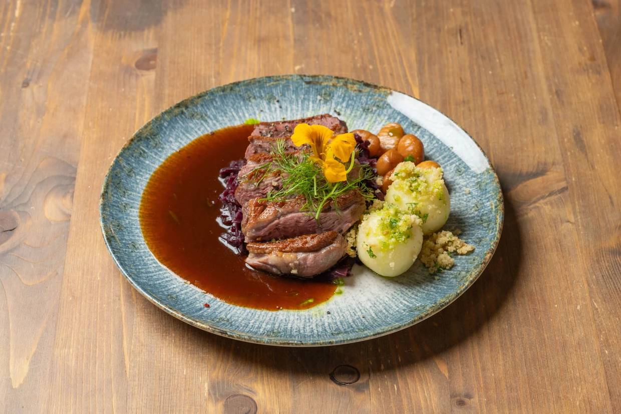 Winterliches Traditionsgericht: Die Gänsebrust wird mit Rotkraut, Knödeln, Maronen und einer kräftigen Schwarzbiersoße serviert.