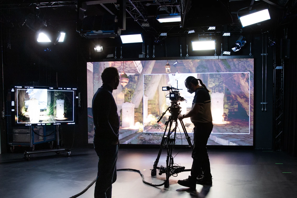 In der Firmenzentrale von dem Kamerahersteller ARRI ist ein Virtual Production Studio eingerichtet. Die Kamerabewegungen werden erfasst und auf ein 3D-Modell übertragen, dass auf eine LED-Wand im Hintergrund projiziert wird.