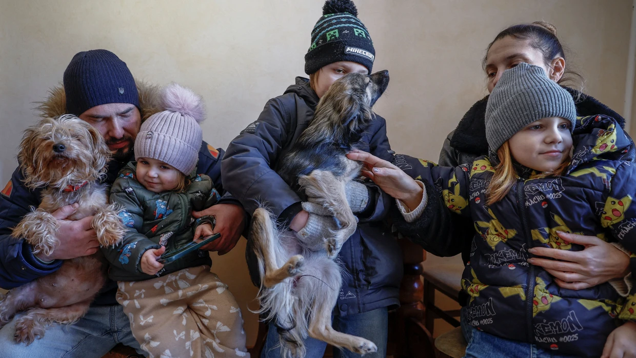 Familie Davydenko, Denys und Yuliia, beide 40, mit Maksym, 11, Tymofiy, 6, Stephanie, 2, sitzen in Winterkleidung in der Küche ihrer unbeheizten Wohnung in Kiew.