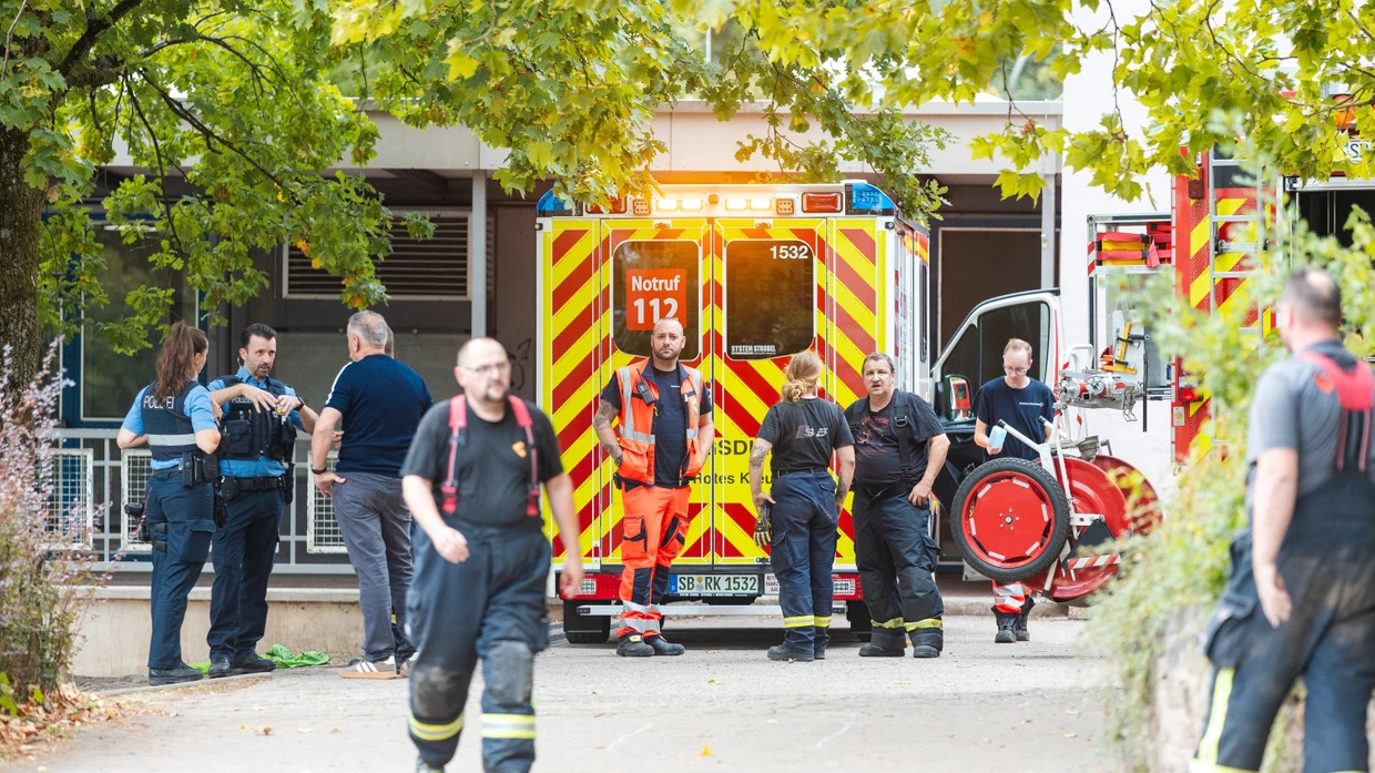 Saarbrücken: Einsatzkräfte von Feuerwehr und Rettungsdienst stehen am Theodor-Heuss-Gymnasium, nachdem ein Kind in einen Schacht gerutscht war.