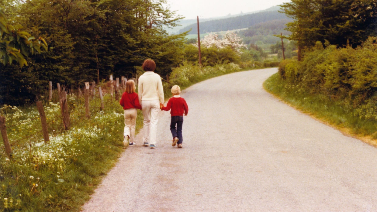 Eine Mutter läuft mit ihrer Tochter und ihrem Sohn über eine Straße.