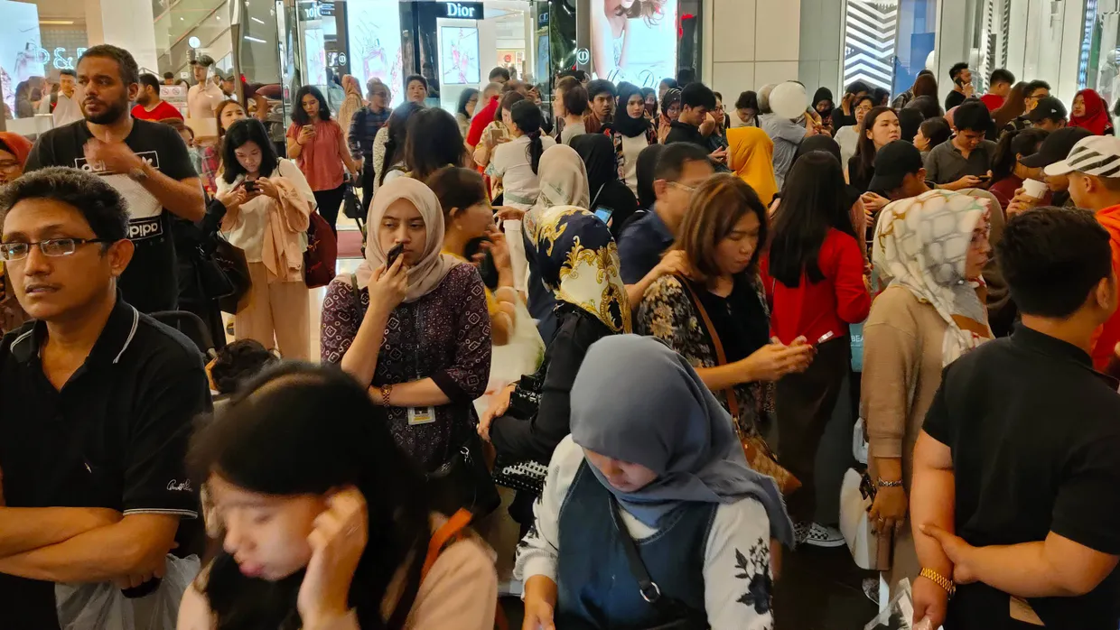 Passanten stehen am Freitagabend vor einem Einkaufszentrum in Jakarta, das evakuiert wurde.