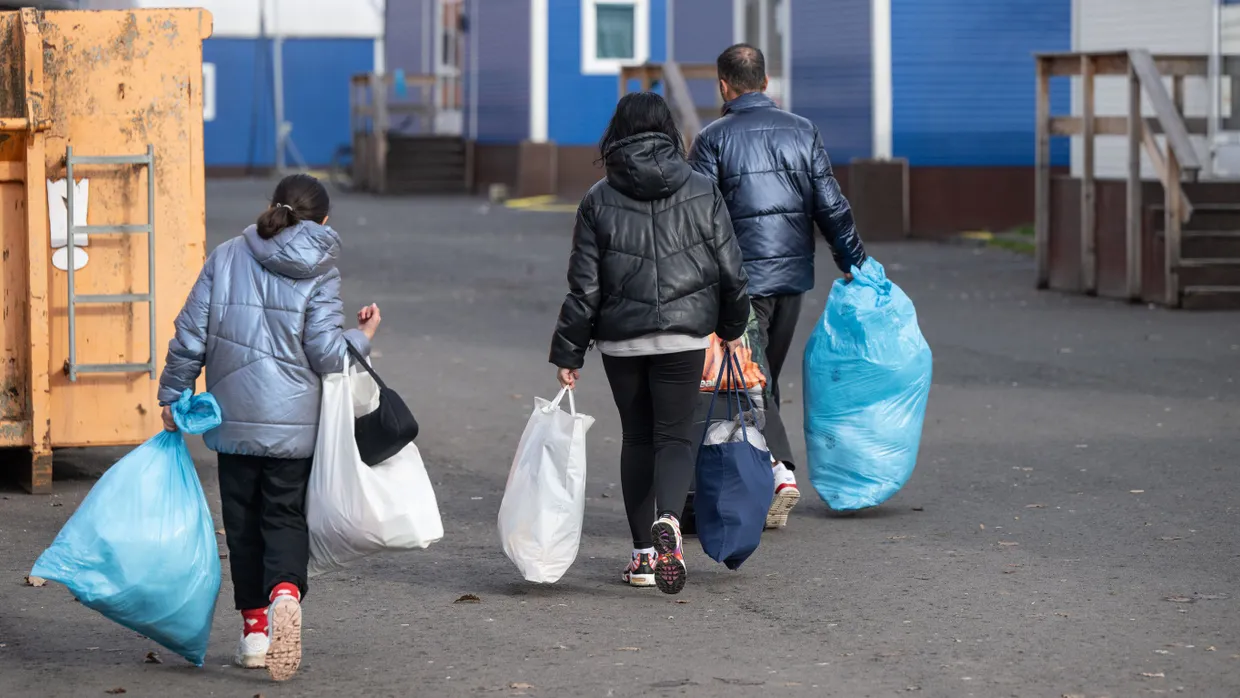 Neu angekommene Flüchtlinge tragen im November 2023 ihre persönlichen Habseligkeiten zu ihrer Unterkunft in der Erstaufnahmeeinrichtung in Gießen.
