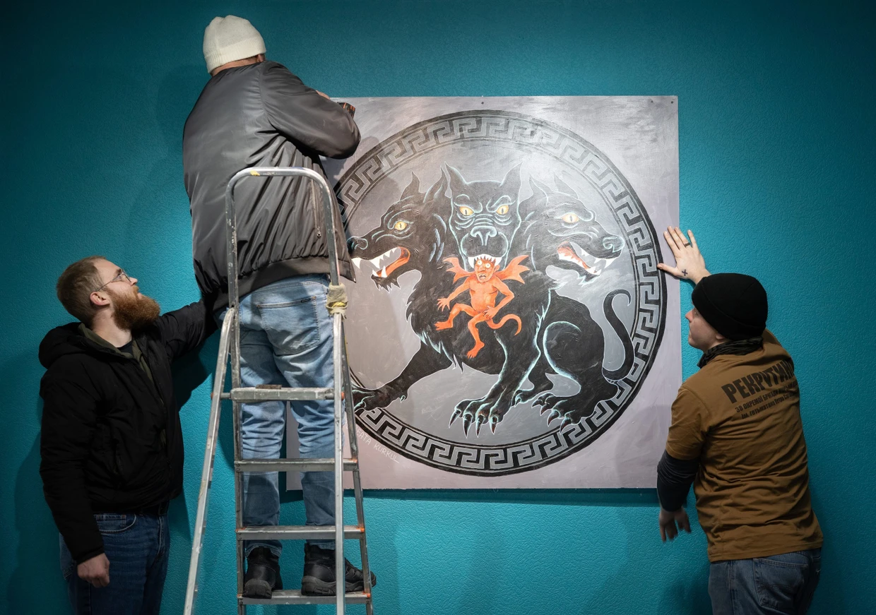 Wladyslaw Schuljak (links) hänngt ein großes Bild des Höllenhuds Kerberos auf.