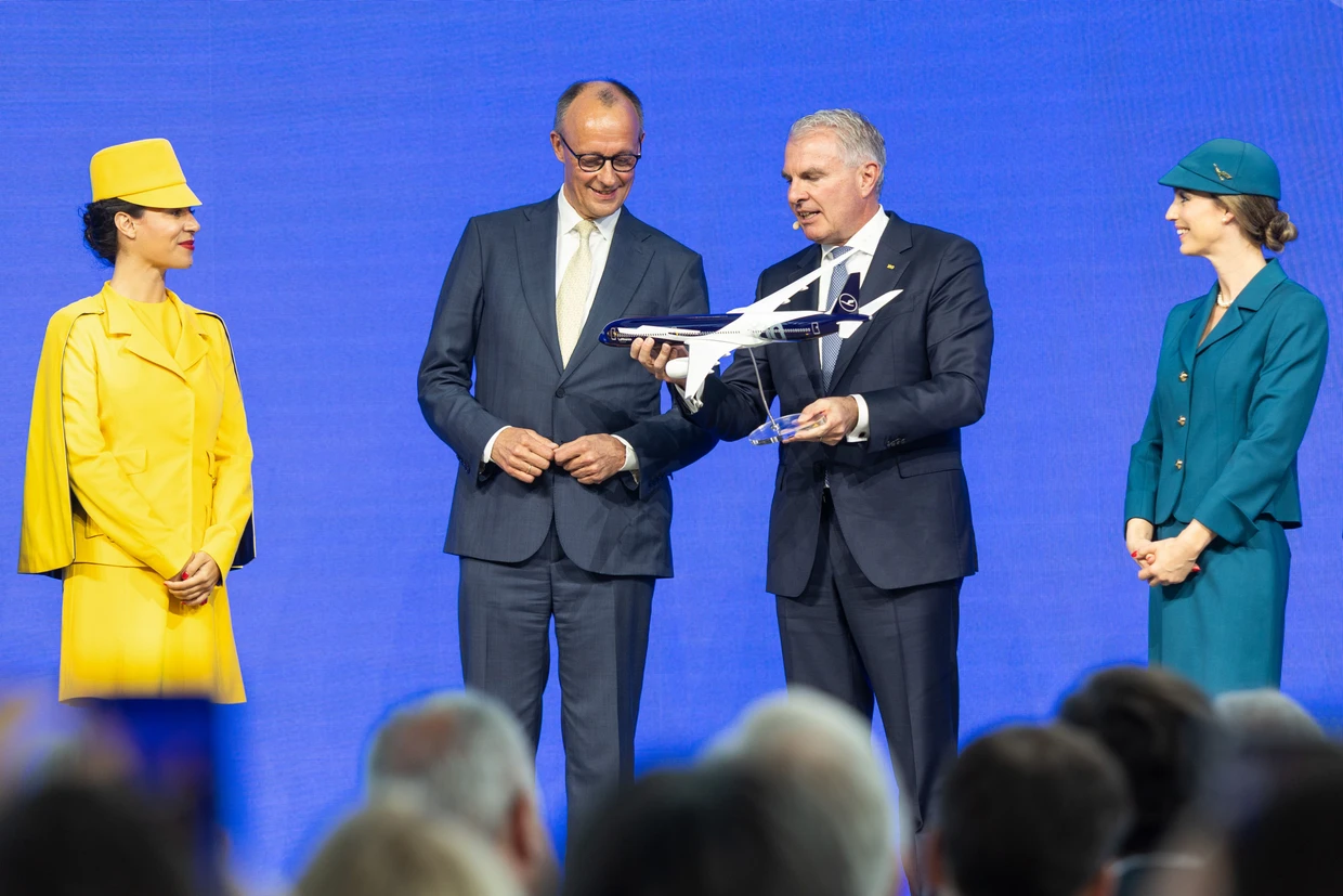 Zum Festakt übergibt Vorstandschef Spohr ein Modell des neuen Jets an Kanzler Merz.