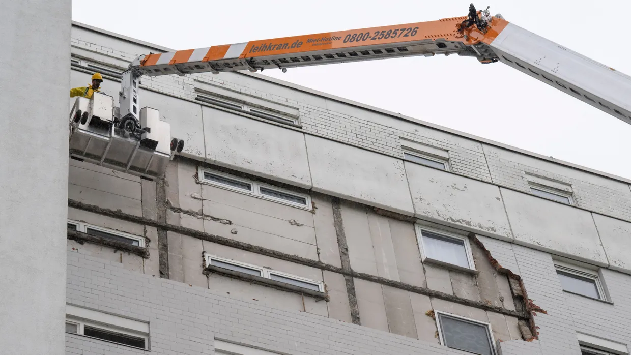 Marode Verkleidung: Mithilfe eines Krans werden lockere Fassadenteile an dem Wohngebäude entfernt.