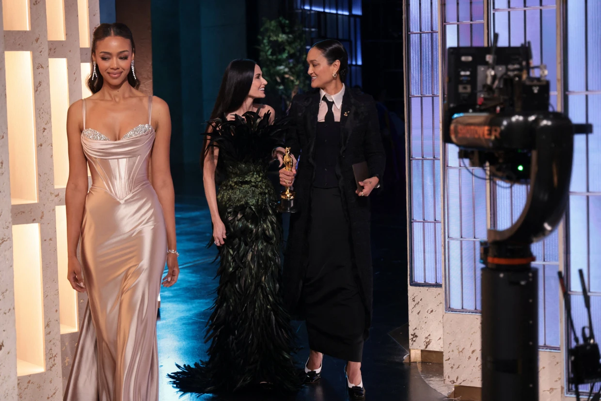 Kamerafrau Autumn Durald Arkapaw (rechts) geht mit ihrem Oscar für „Blood&Sinners“ in Begleitung von Demi Moore (Mitte) von der Bühne.