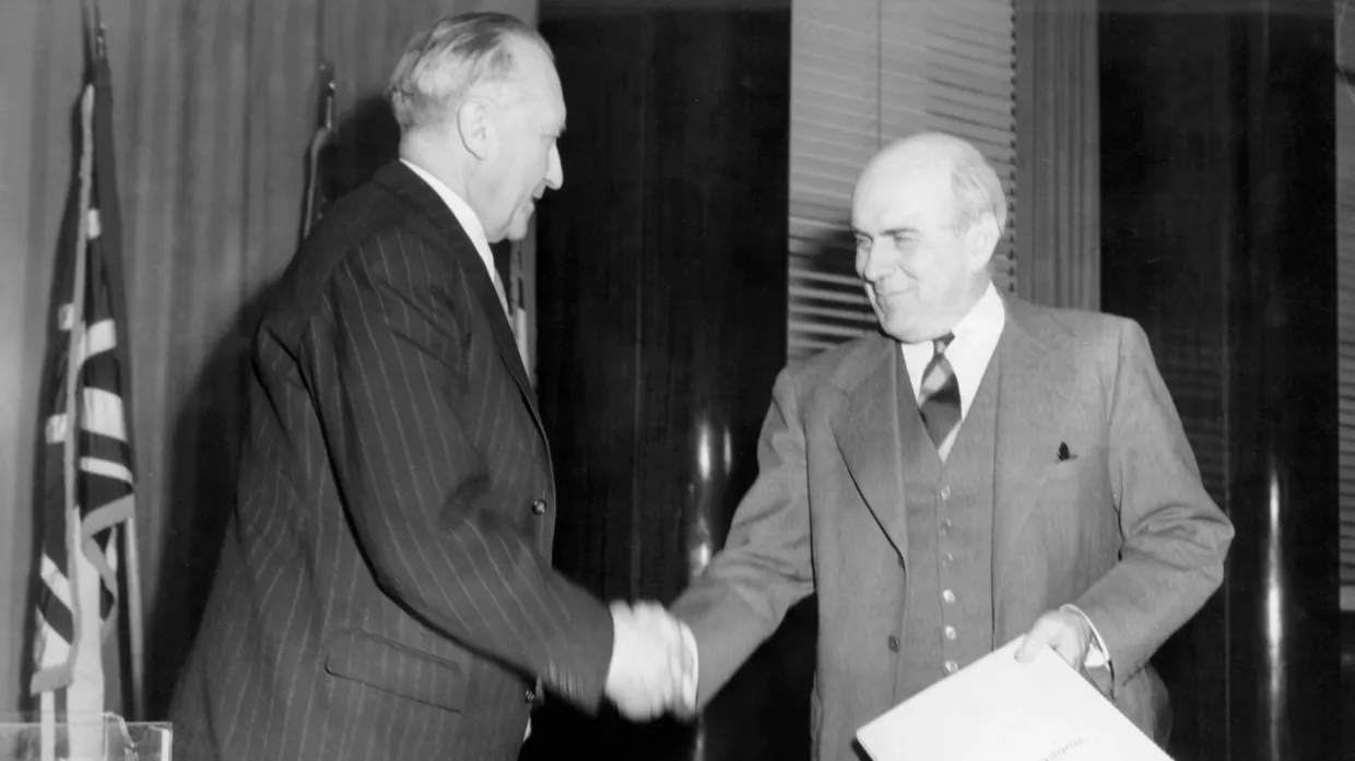 Ein großer Moment für die junge Bundesrepublik: Im IG-Farben-Haus in Frankfurt überreicht Bundeskanzler Konrad Adenauer (links) 1950 dem amerikanischen Hochkommissar John McCloy die Urkunde über die Ratifizierung eines Wirtschaftsabkommens zwischen den beiden Ländern – der erste völkerrechtliche Vertrag des neuen Staates.