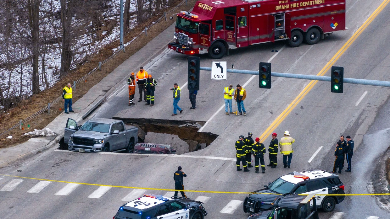 Polizei und Feuerwehr untersuchen zwei Fahrzeuge, die auf der Pacific Street östlich der 67th Street in Omaha in ein Sinkloch gestürzt sind.