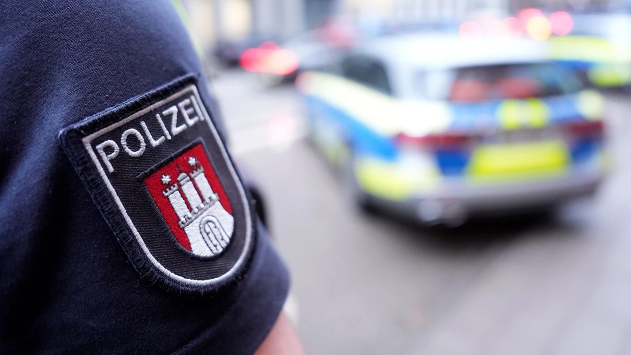 Ein Polizist steht vor einem Einsatzfahrzeug der Polizei Hamburg (Archivbild).