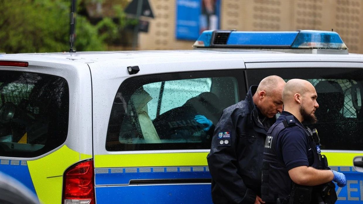 Zwei Polizisten stehen während eines Großeinsatzes in Witten neben einem Einsatzwagen.