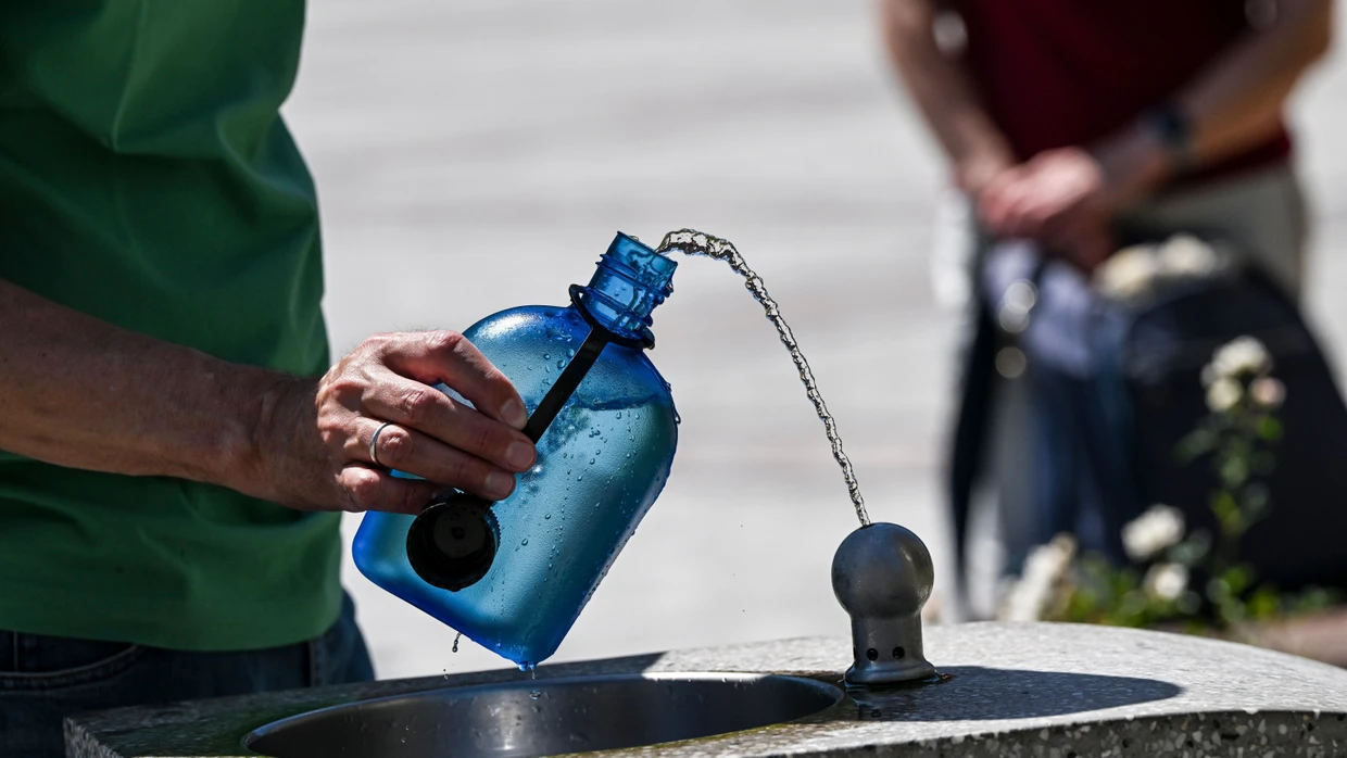 Es ist und bleibt heiß: Ein Mann nutzt auf dem Gendarmenmarkt in Berlin einen Wasserspender, um seine Trinkflasche aufzufüllen.