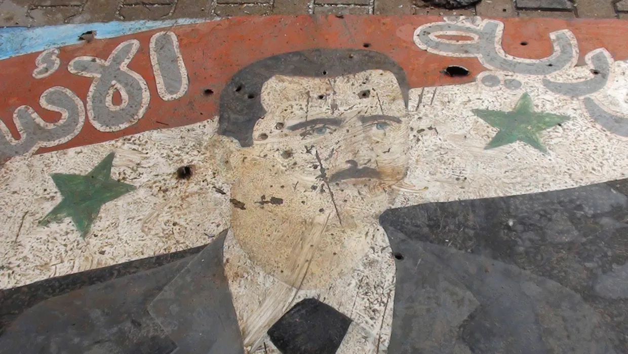 Ein Plakat von Syriens Präsident Assad ist in Homs unter Beschuss geraten