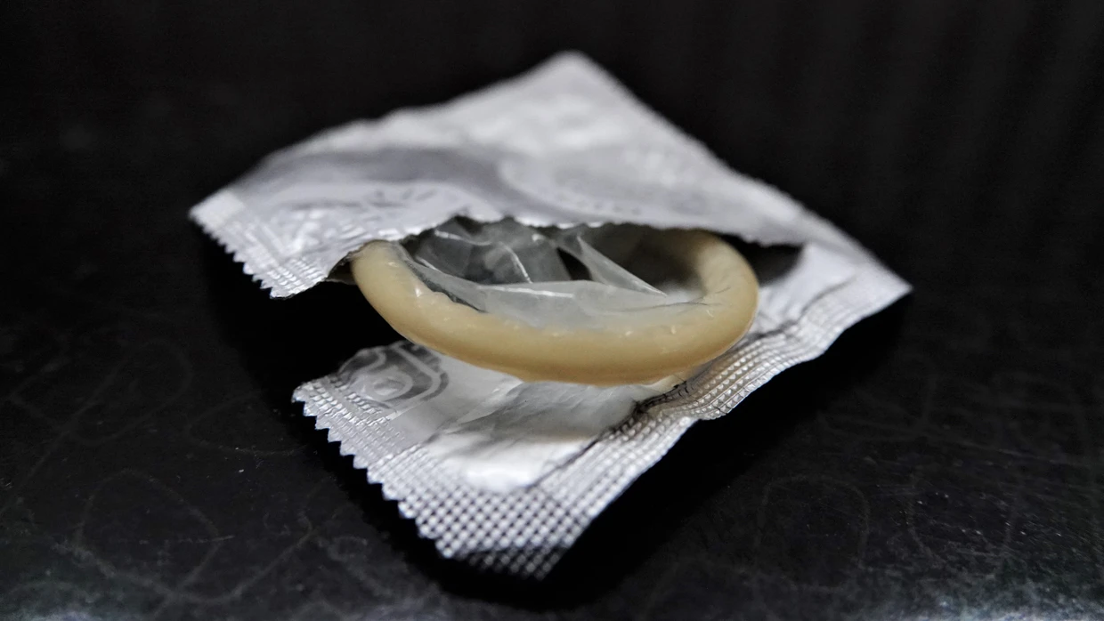 Bitte auf die CE-Markierung achten: Eine geöffnete Kondompackung liegt neben einem Bett auf einem Nachttisch. (Symbolbild)