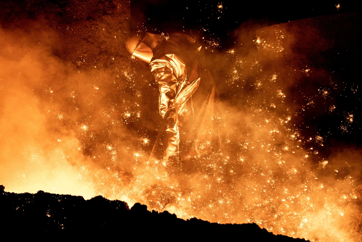 Stahlproduktion bei Salzgitter. Ein Mitarbeiter reinigt die Abstichrinne am Hochofen.