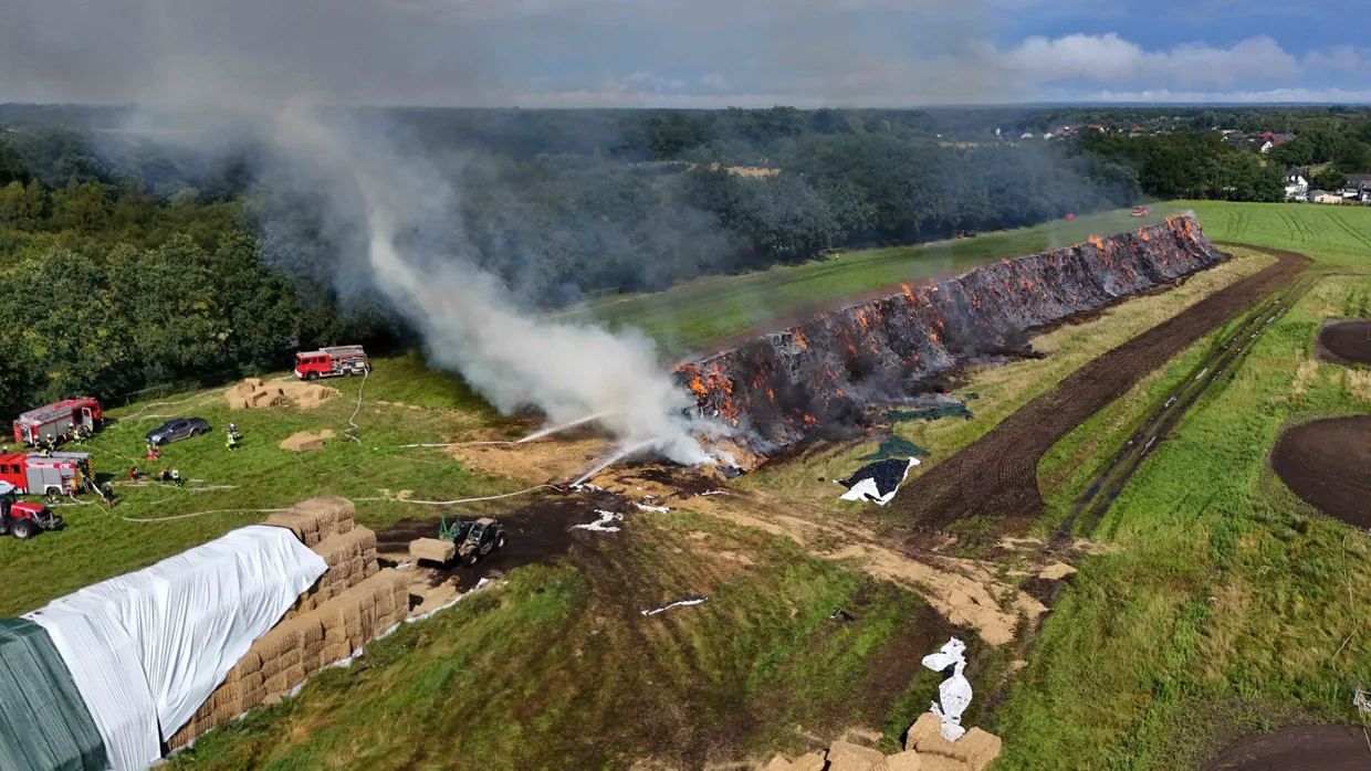 Durch Blitzeinschlag: Feuerwehrleute bekämpfen ein Feuer, bei dem Strohballen brennen.